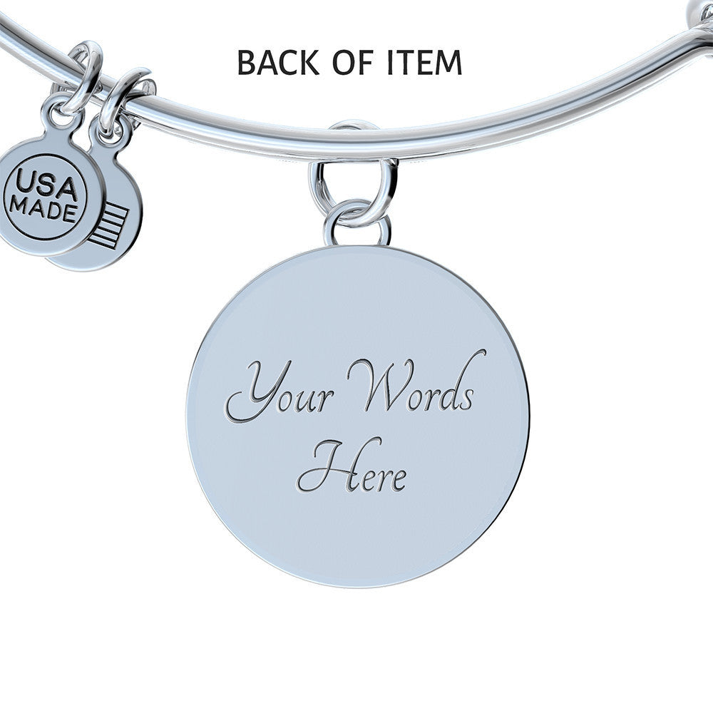 The Aries Zodiac Bangle Bracelet With Optional Personalization by ShineOn Fulfillment features a round charm engraved with the words "Your Words Here." Additional smaller charms with "USA MADE" text are attached. Crafted from high quality surgical steel, this piece of personalized jewelry ensures lasting durability. Text on the image states "BACK OF ITEM.