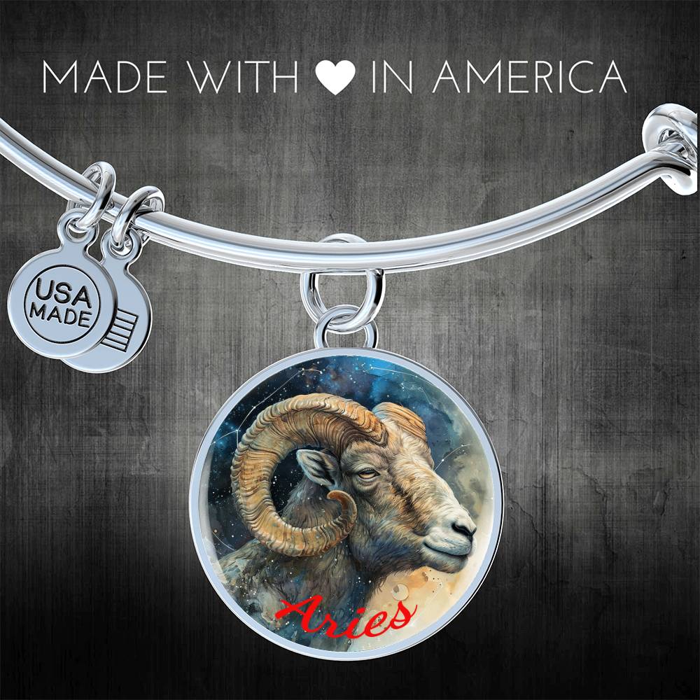 A silver bracelet with a round charm depicting a ram, representing the Aries zodiac sign, with "Aries" written in red. Crafted from high quality surgical steel, the bracelet features a small tag with "USA Made" on it. With custom engraving options available, it reads "Made with ♥ in America.

Product: ShineOn Fulfillment’s Aries Zodiac Bangle Bracelet With Optional Personalization